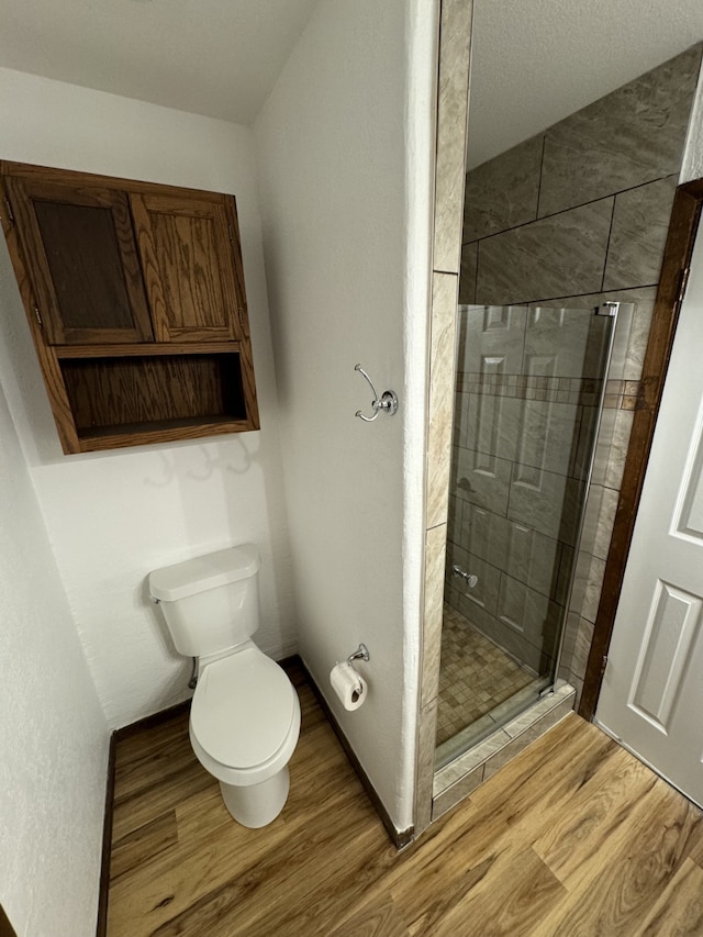 bathroom featuring hardwood / wood-style floors, an enclosed shower, and toilet