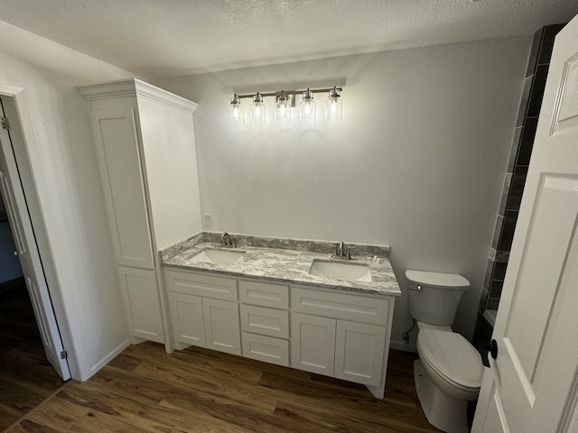 bathroom with hardwood / wood-style flooring, vanity, toilet, and a textured ceiling