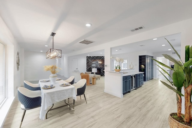 dining room with light wood-type flooring, visible vents, recessed lighting, and wine cooler