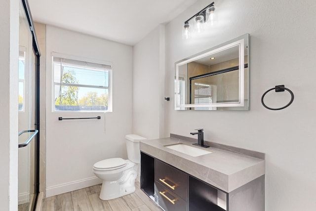 bathroom featuring hardwood / wood-style flooring, vanity, toilet, and a shower with door