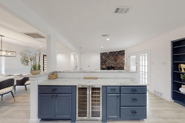 bar with wine cooler, visible vents, and light wood-style flooring