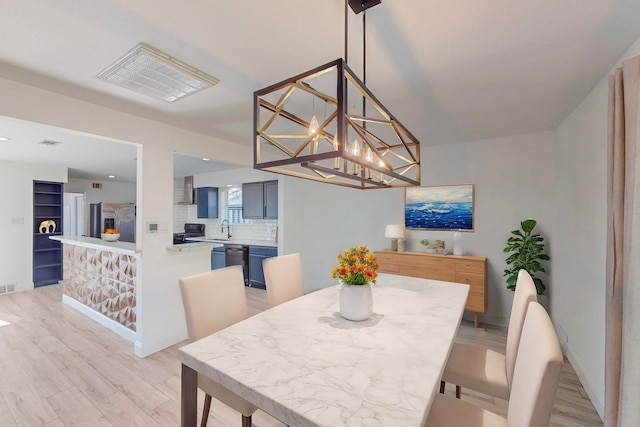 dining room with light hardwood / wood-style floors, a notable chandelier, and sink