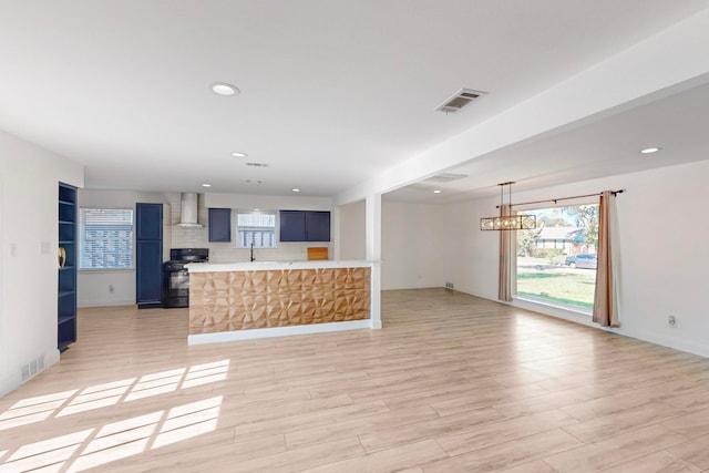 kitchen with gas stove, wall chimney range hood, and light hardwood / wood-style flooring