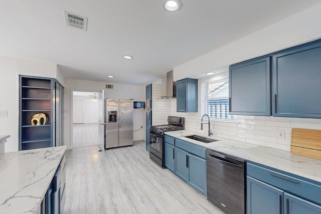 kitchen featuring light stone countertops, sink, wall chimney range hood, light hardwood / wood-style flooring, and black appliances