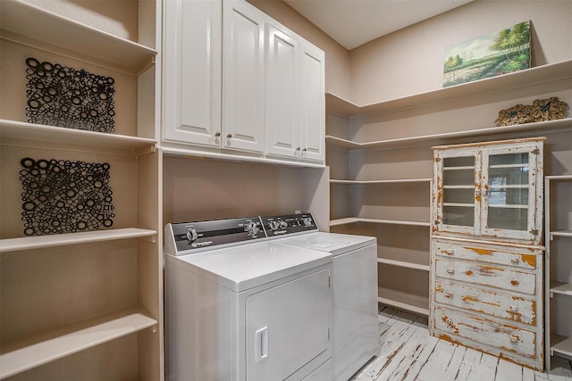 clothes washing area featuring cabinets and washing machine and clothes dryer