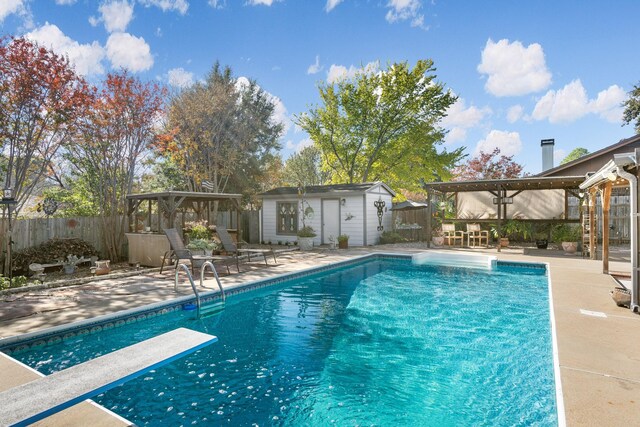 view of swimming pool featuring a gazebo, a diving board, an outbuilding, and a patio