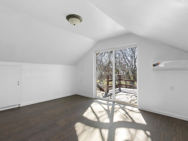 additional living space featuring dark wood-type flooring and vaulted ceiling