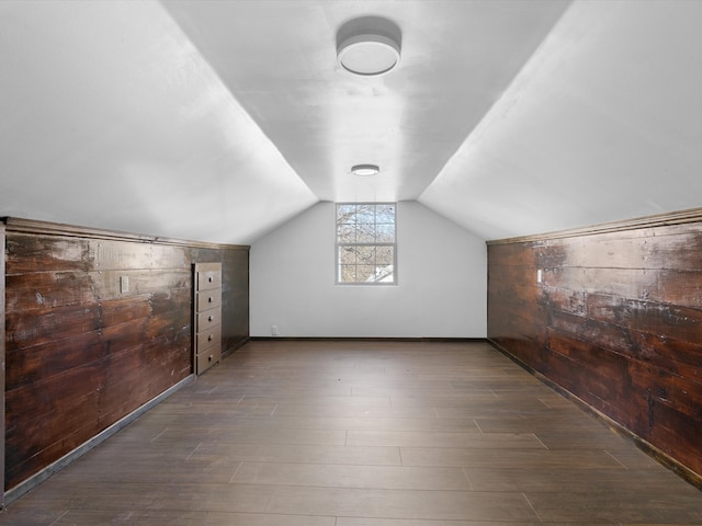 additional living space featuring wooden walls, dark hardwood / wood-style floors, and vaulted ceiling