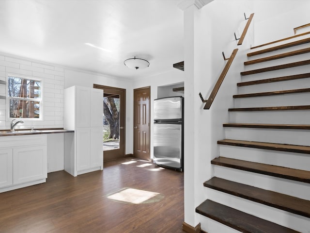 interior space featuring sink, dark wood-type flooring, stainless steel refrigerator, tasteful backsplash, and white cabinets