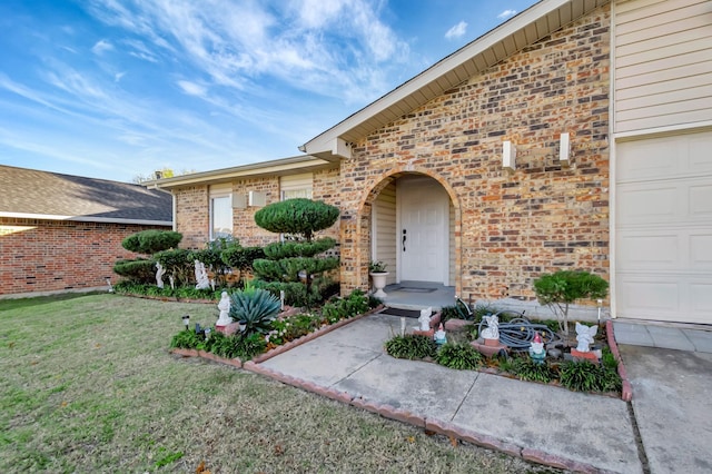 property entrance with a garage, brick siding, and a yard