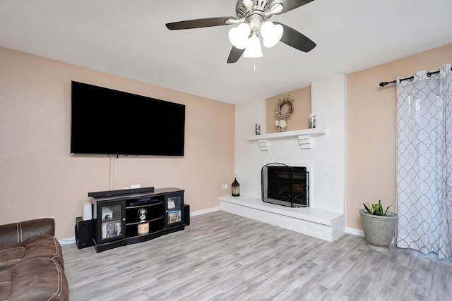 living room with ceiling fan, light wood finished floors, a fireplace, and baseboards