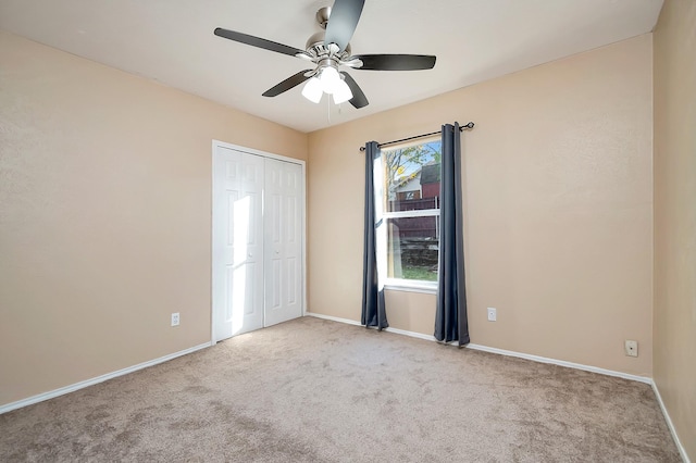 unfurnished bedroom featuring a ceiling fan, baseboards, a closet, and light colored carpet