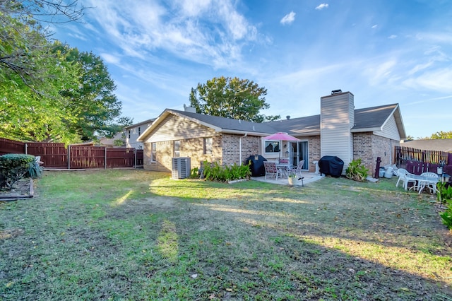 rear view of property with a patio, a chimney, a fenced backyard, and a lawn