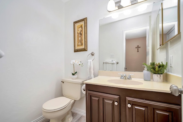 bathroom featuring toilet, baseboards, and vanity