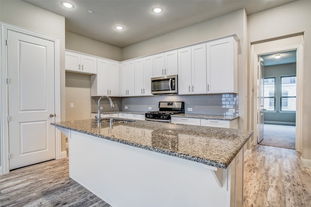 kitchen with light hardwood / wood-style floors, white cabinetry, sink, and appliances with stainless steel finishes