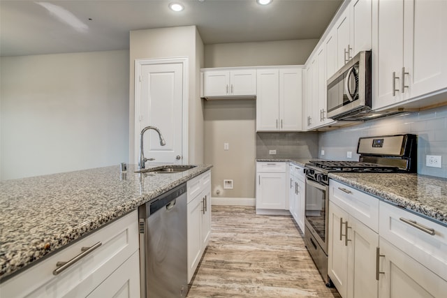 kitchen with light stone countertops, appliances with stainless steel finishes, sink, and white cabinets