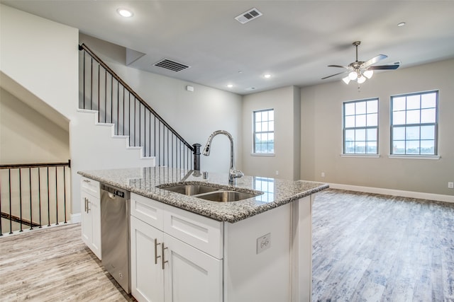 kitchen featuring white cabinets, stainless steel dishwasher, light stone countertops, and sink