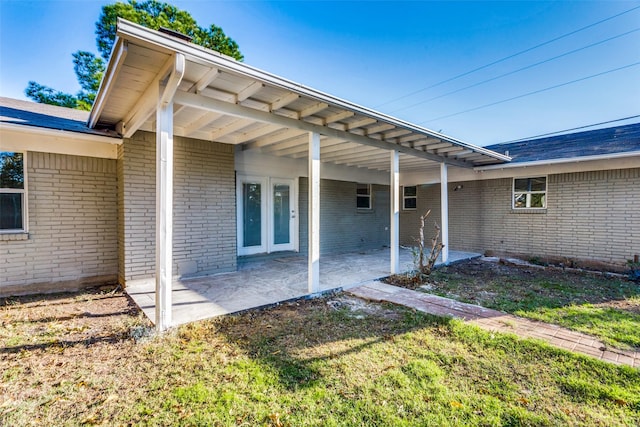 view of exterior entry with a lawn and a patio area