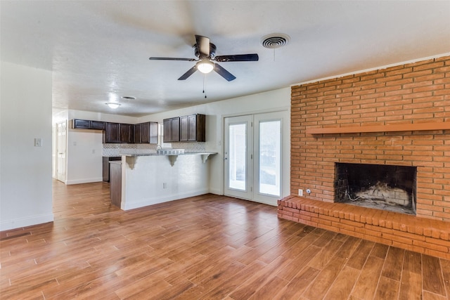 kitchen with dark brown cabinetry, light wood-type flooring, kitchen peninsula, and a kitchen bar