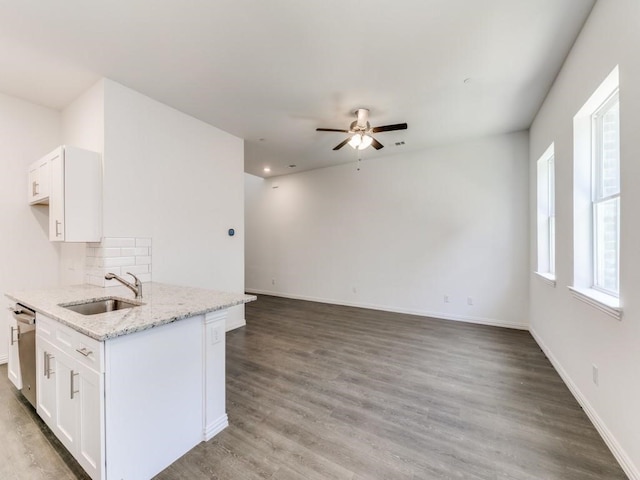 kitchen with dishwasher, white cabinetry, wood-type flooring, sink, and light stone counters