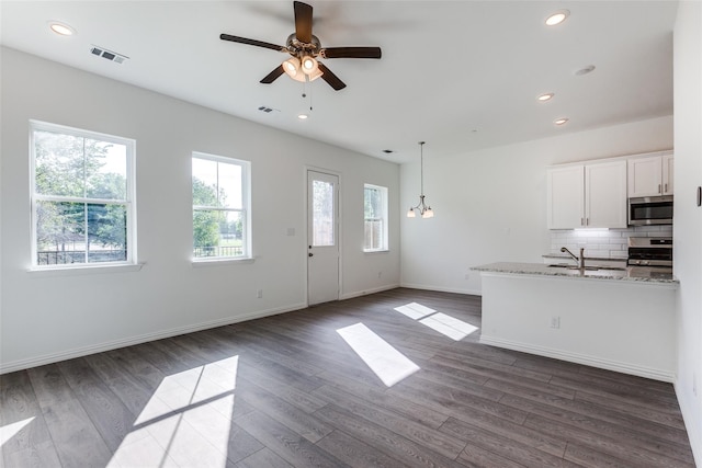 kitchen featuring pendant lighting, white cabinets, decorative backsplash, stove, and light stone countertops