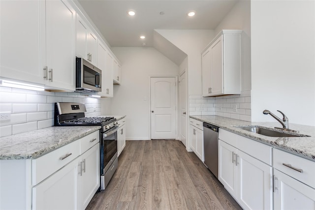 kitchen featuring sink, white cabinets, stainless steel appliances, light stone countertops, and light hardwood / wood-style flooring