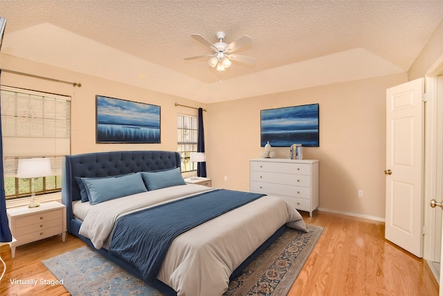 bedroom with ceiling fan, light hardwood / wood-style floors, and a textured ceiling