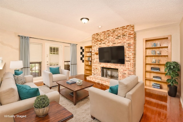 living room featuring a textured ceiling, built in features, lofted ceiling, and a fireplace