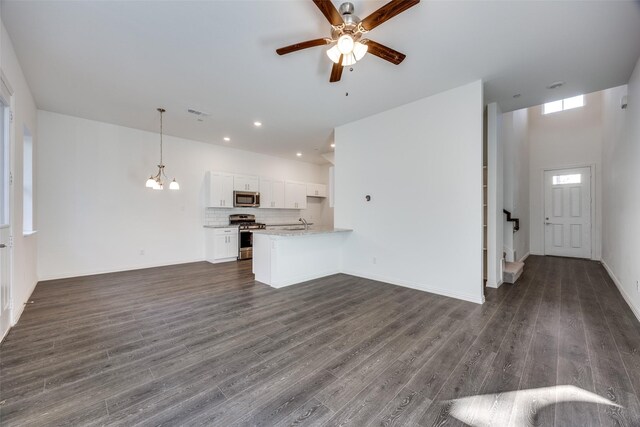 unfurnished living room featuring ceiling fan with notable chandelier, sink, and dark wood-type flooring