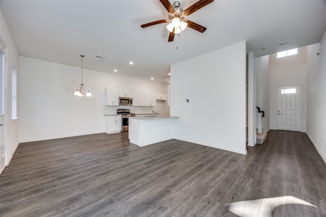 unfurnished living room with sink, ceiling fan with notable chandelier, and dark hardwood / wood-style floors