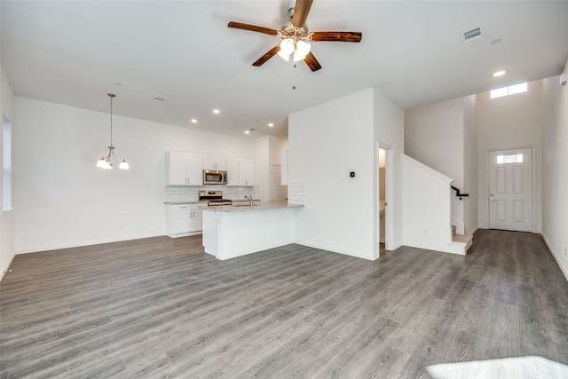 unfurnished living room with a high ceiling, wood-type flooring, sink, and ceiling fan with notable chandelier