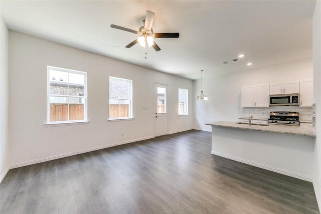 kitchen with light stone counters, tasteful backsplash, pendant lighting, stainless steel appliances, and white cabinets