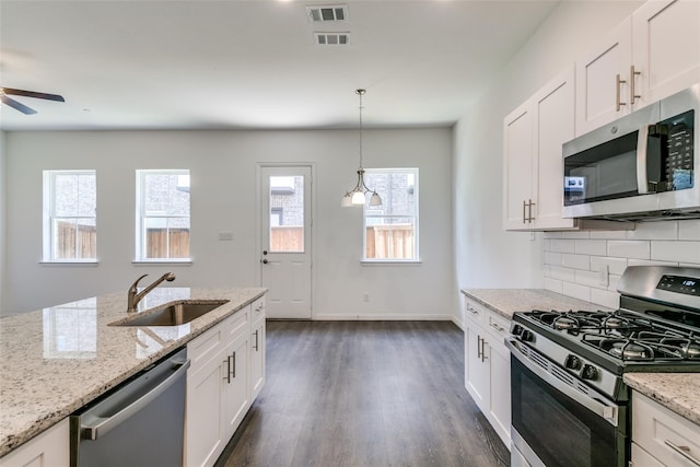 kitchen with white cabinetry, stainless steel appliances, sink, and light stone counters