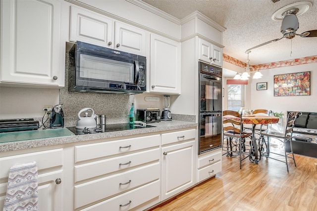 kitchen with black appliances, ceiling fan, light wood-type flooring, a textured ceiling, and white cabinetry