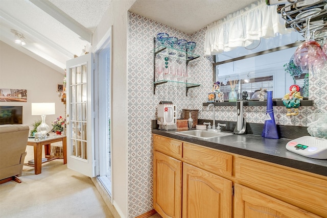 kitchen featuring a textured ceiling, light colored carpet, sink, light brown cabinets, and lofted ceiling