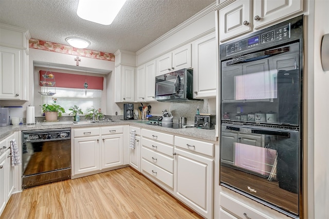 kitchen featuring black appliances, white cabinets, light wood-type flooring, and a textured ceiling