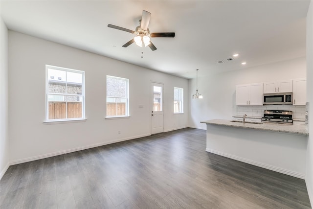 kitchen with white cabinets, appliances with stainless steel finishes, light stone counters, and a wealth of natural light