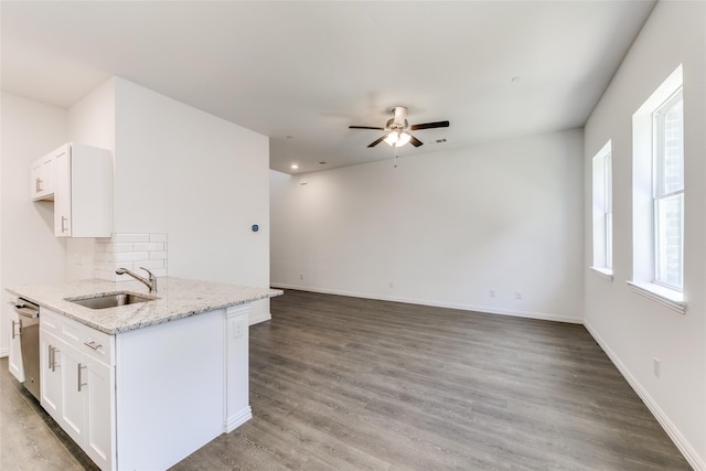 kitchen with white cabinets, hardwood / wood-style flooring, light stone counters, and sink