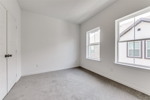 unfurnished room featuring light colored carpet and lofted ceiling