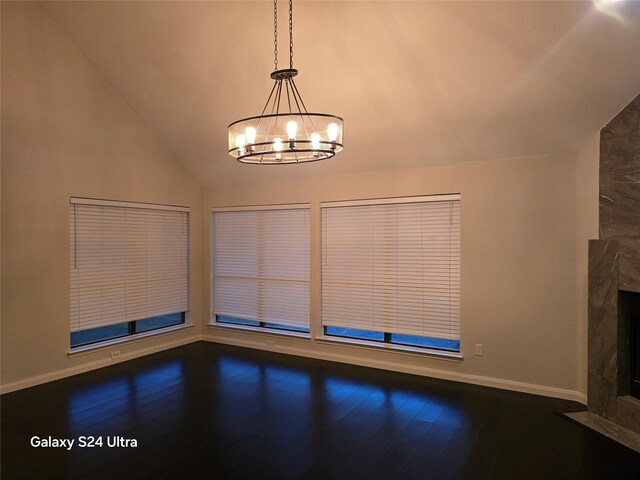 unfurnished living room with hardwood / wood-style flooring, vaulted ceiling, a premium fireplace, and a chandelier