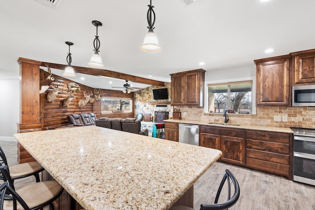 kitchen featuring a kitchen island, appliances with stainless steel finishes, decorative light fixtures, sink, and a kitchen breakfast bar