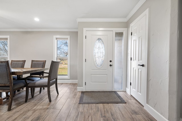 foyer featuring crown molding, wood-type flooring, and a healthy amount of sunlight