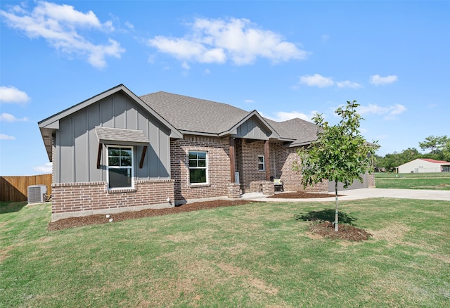 view of front facade with a garage, central air condition unit, and a front lawn