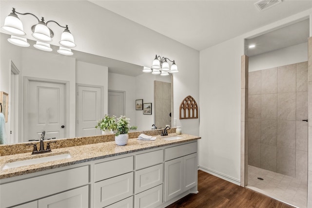 bathroom featuring tiled shower, vanity, a notable chandelier, and hardwood / wood-style flooring