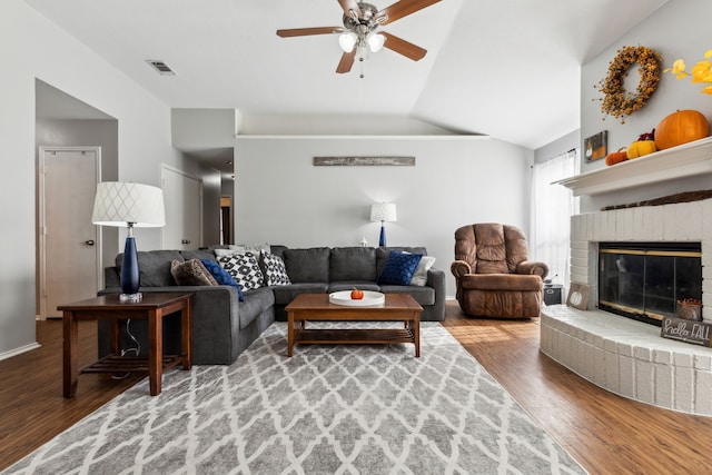 living room with hardwood / wood-style flooring, ceiling fan, lofted ceiling, and a brick fireplace