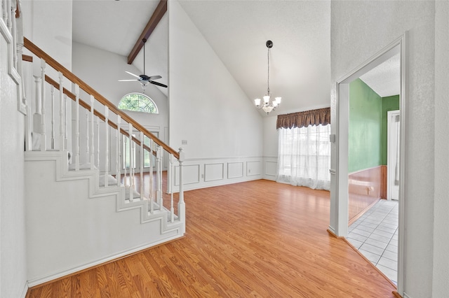 foyer with light hardwood / wood-style flooring, beamed ceiling, ceiling fan with notable chandelier, and high vaulted ceiling