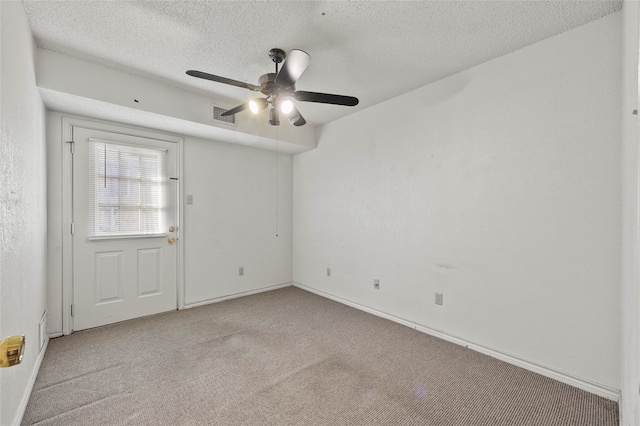 empty room with ceiling fan, light colored carpet, and a textured ceiling