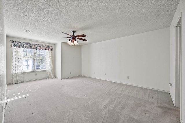 spare room featuring ceiling fan, light colored carpet, and a textured ceiling