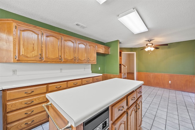 kitchen featuring a textured ceiling, a kitchen island, ceiling fan, and light tile patterned flooring