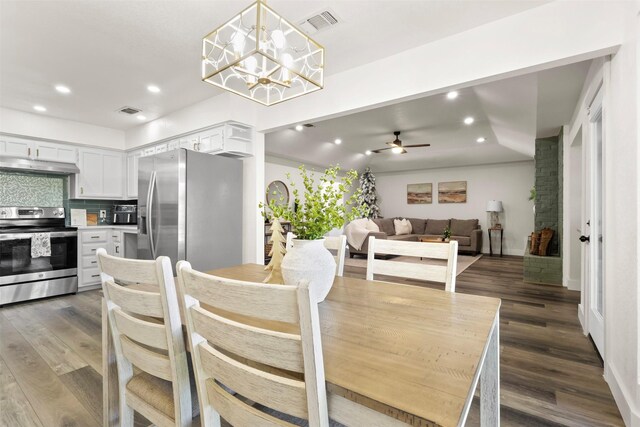 dining room with ceiling fan with notable chandelier and dark hardwood / wood-style flooring